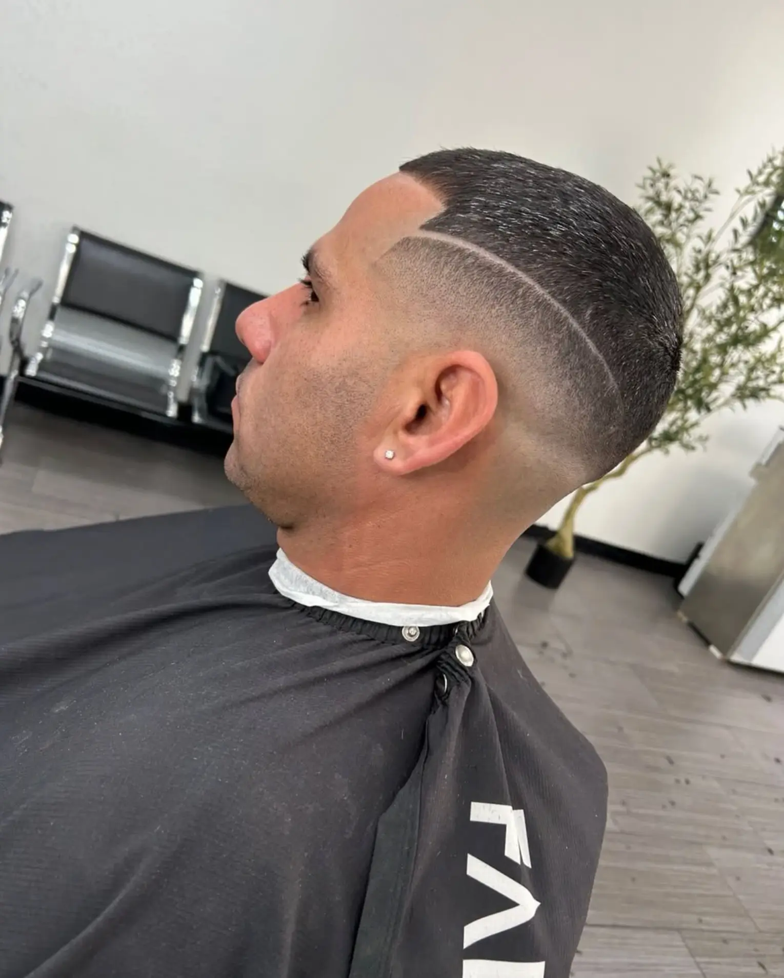 Client in a red barber cape with a freshly styled fade haircut